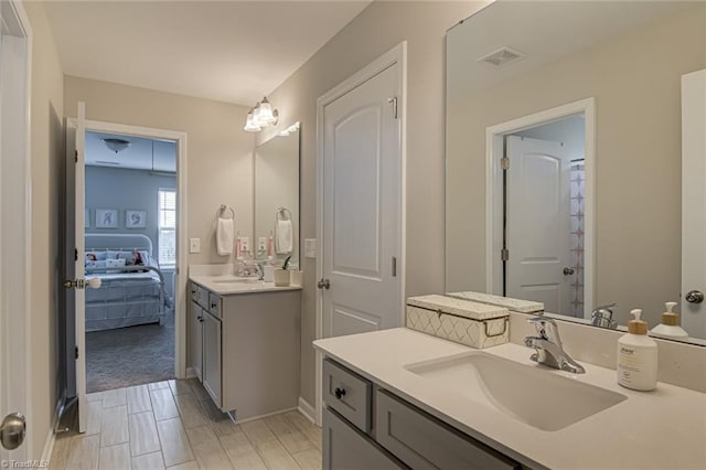 ensuite bathroom featuring two vanities, a sink, visible vents, and connected bathroom