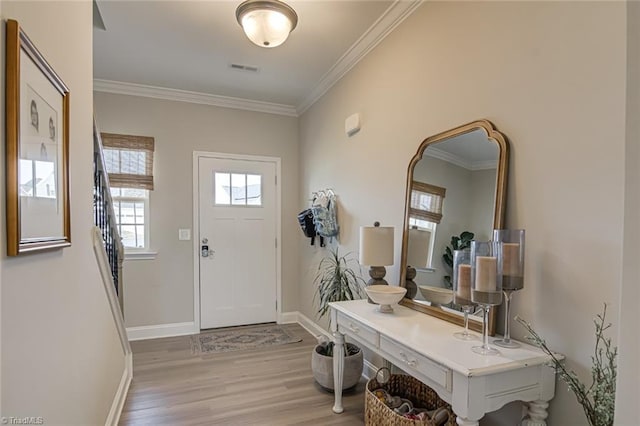 entrance foyer featuring ornamental molding, light wood-type flooring, visible vents, and baseboards