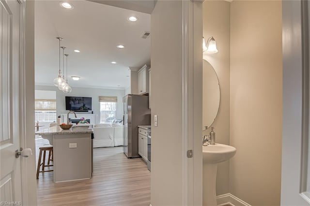 interior space featuring light wood finished floors, a breakfast bar area, visible vents, freestanding refrigerator, and open floor plan