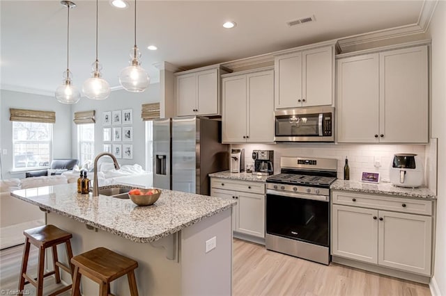 kitchen featuring a breakfast bar, crown molding, stainless steel appliances, visible vents, and open floor plan