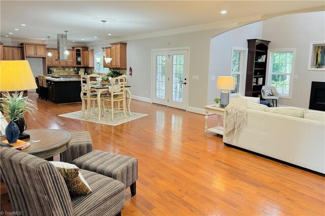 kitchen with decorative backsplash, light stone counters, a kitchen island, light hardwood / wood-style flooring, and island range hood