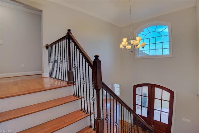 stairway featuring wood-type flooring, a chandelier, and ornamental molding