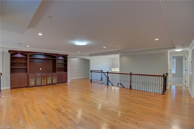 unfurnished living room with a chandelier, light wood-type flooring, crown molding, and a raised ceiling