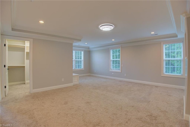 unfurnished room featuring a raised ceiling, ornamental molding, and light colored carpet