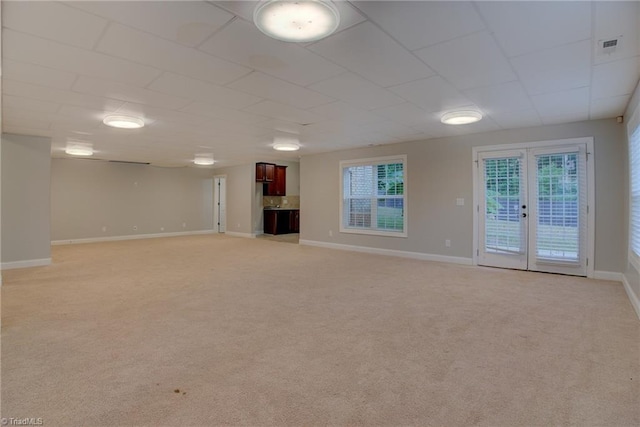 unfurnished living room with french doors, a drop ceiling, and carpet flooring