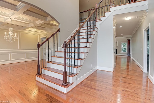 staircase featuring ornamental molding, beam ceiling, coffered ceiling, and hardwood / wood-style flooring