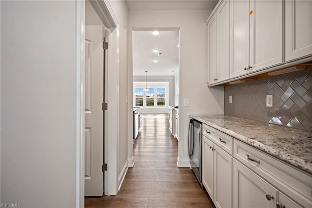 kitchen featuring white cabinets, backsplash, light stone countertops, and dark wood-type flooring