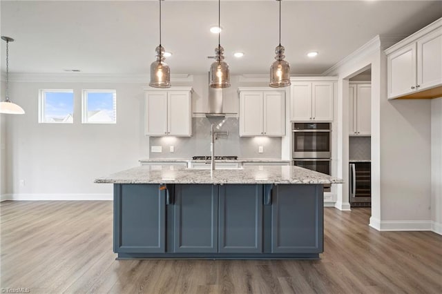 kitchen featuring pendant lighting, light stone countertops, white cabinetry, and a center island with sink