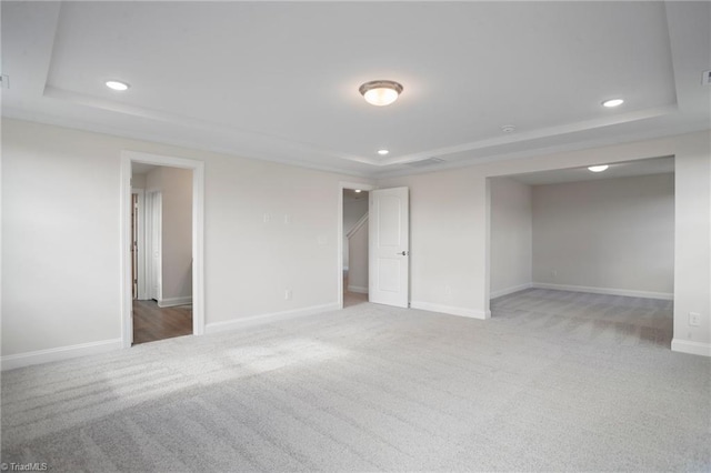 empty room with a raised ceiling and carpet floors