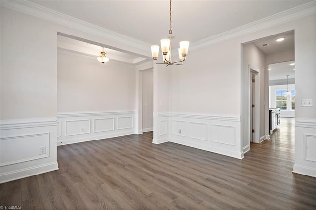 empty room featuring dark hardwood / wood-style floors, an inviting chandelier, and ornamental molding