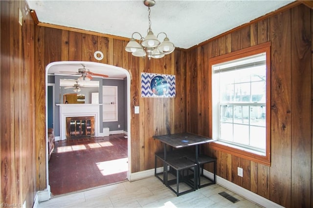 dining room featuring wooden walls and ceiling fan with notable chandelier