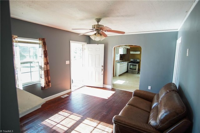 living room featuring ceiling fan, ornamental molding, and light hardwood / wood-style floors