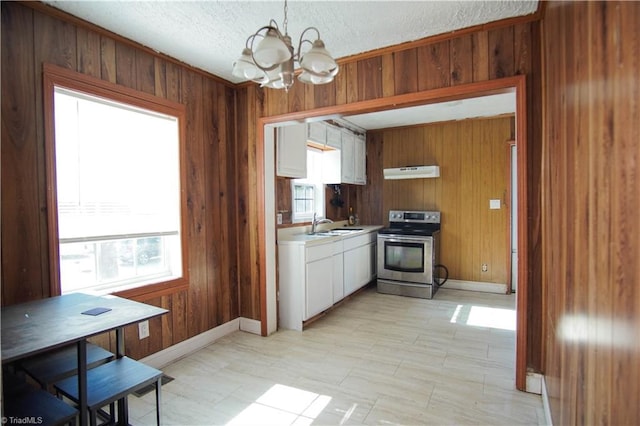 kitchen featuring stainless steel range with electric stovetop, white cabinetry, a notable chandelier, decorative light fixtures, and wood walls