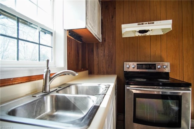 kitchen with stainless steel electric stove, sink, and white cabinets