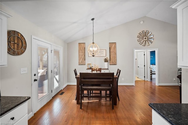 dining room with lofted ceiling, a chandelier, wood finished floors, visible vents, and french doors