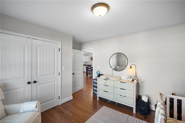 bedroom with a closet, dark wood-style flooring, and baseboards