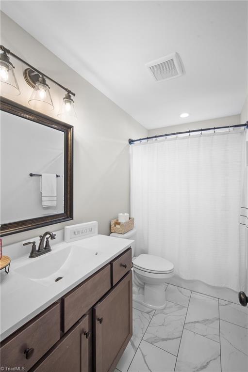 full bath with toilet, marble finish floor, visible vents, and vanity