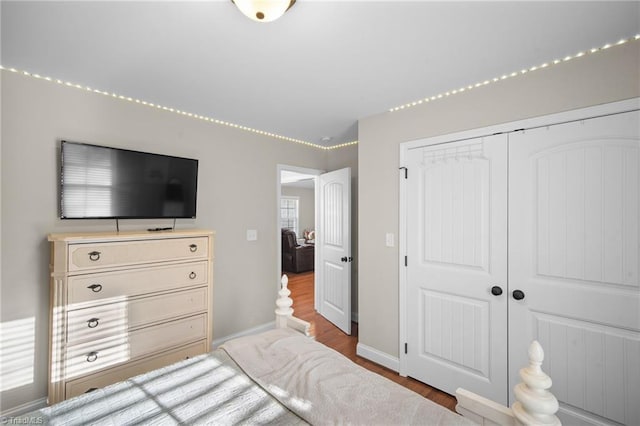 bedroom with a closet, wood finished floors, and baseboards