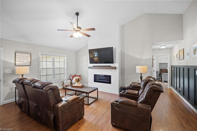 living room featuring a fireplace, wood finished floors, a ceiling fan, and baseboards