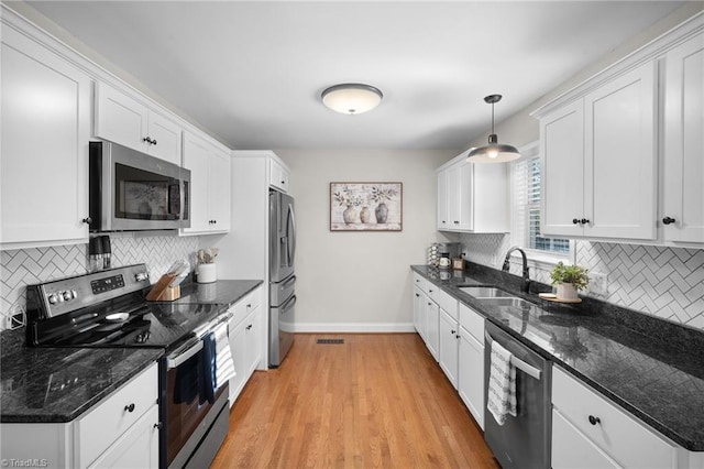 kitchen featuring stainless steel appliances, white cabinetry, and pendant lighting