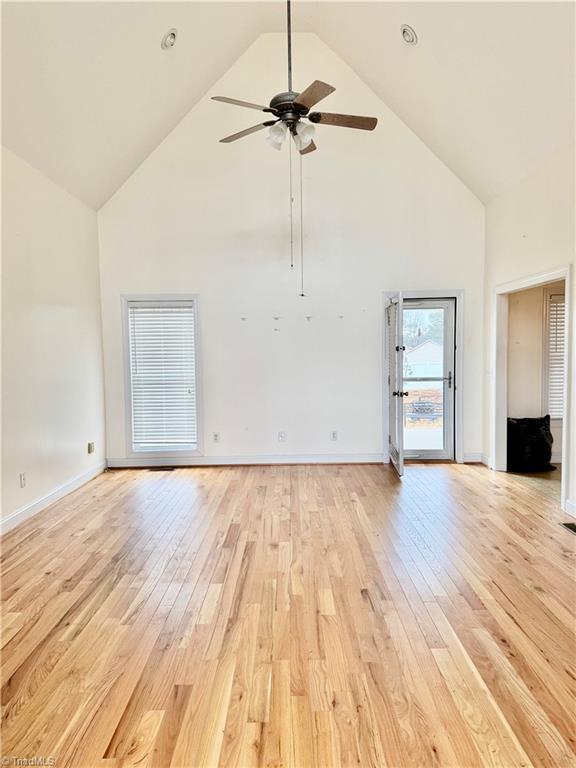 unfurnished living room featuring light hardwood / wood-style floors, high vaulted ceiling, and ceiling fan