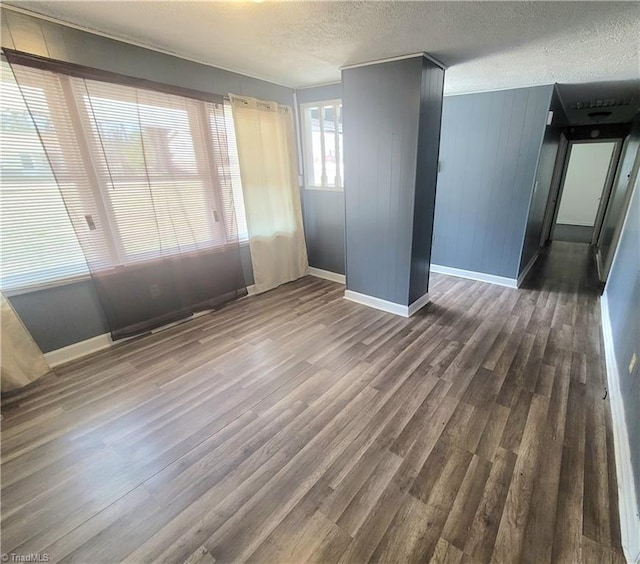 unfurnished room featuring a textured ceiling, dark wood finished floors, and baseboards