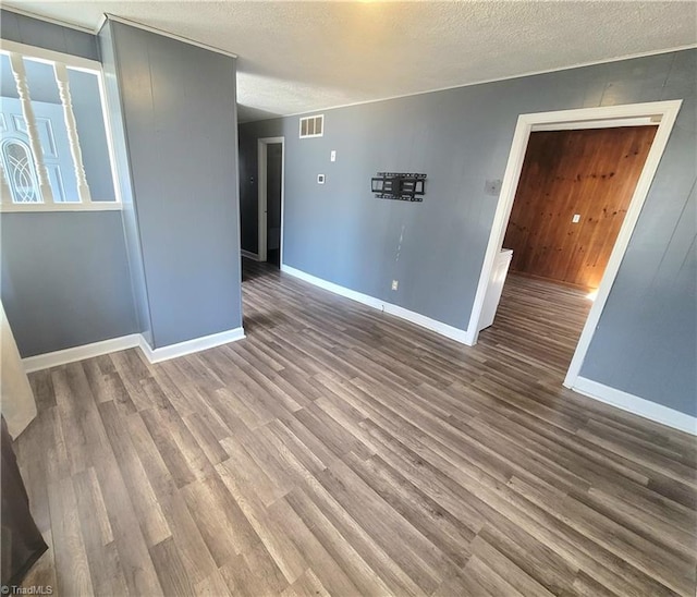 empty room with a textured ceiling, baseboards, and wood finished floors