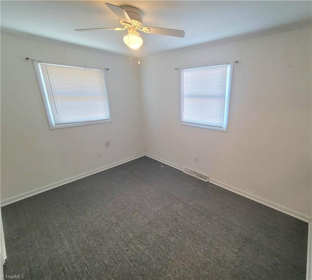 empty room featuring baseboards, visible vents, a ceiling fan, ornamental molding, and dark colored carpet