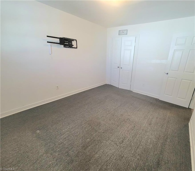 empty room with dark colored carpet and baseboards