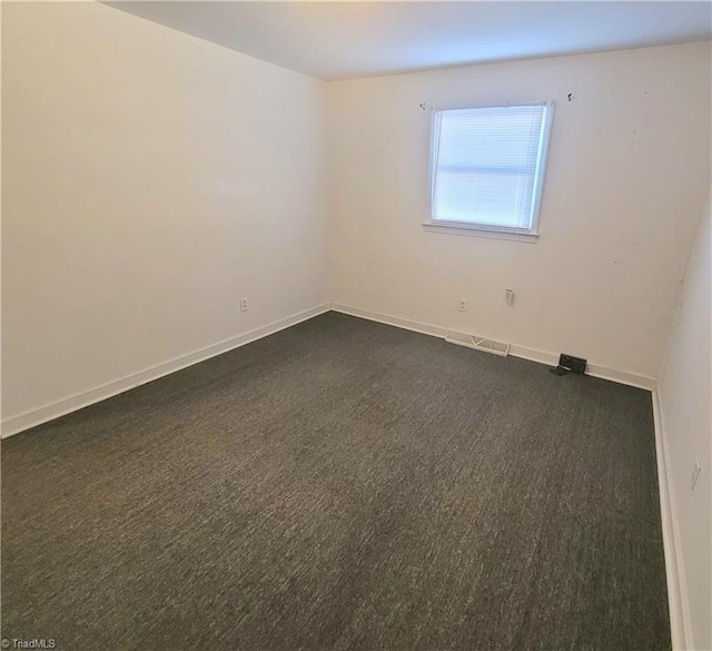 unfurnished room featuring visible vents, dark carpet, and baseboards