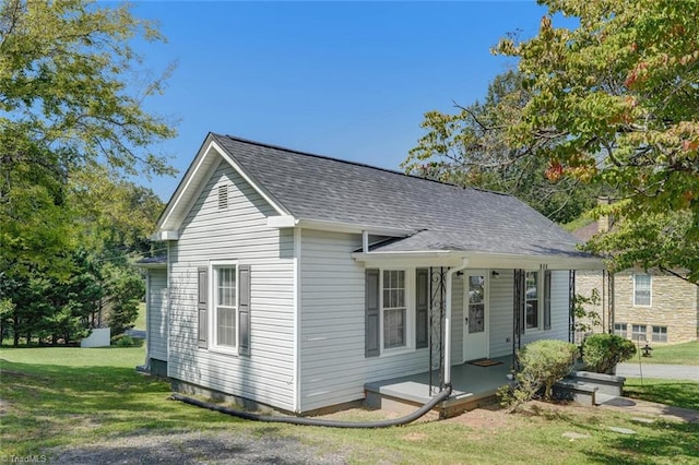 view of front of house featuring covered porch, a front lawn, and a shingled roof