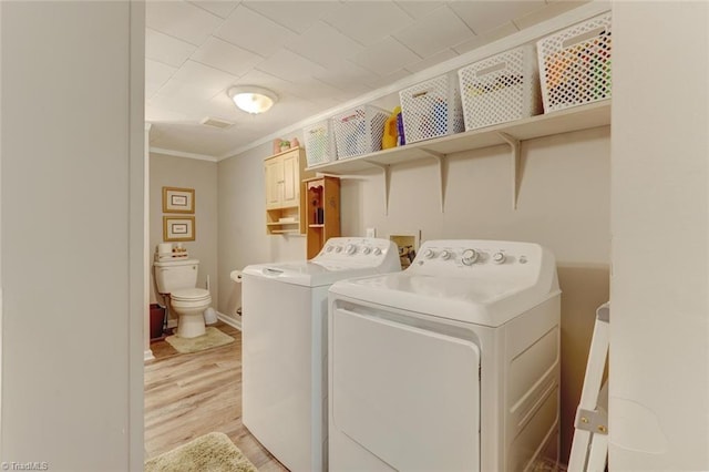 clothes washing area with light wood finished floors, baseboards, ornamental molding, laundry area, and separate washer and dryer