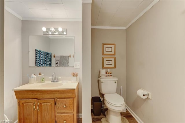 bathroom with vanity, crown molding, toilet, and baseboards