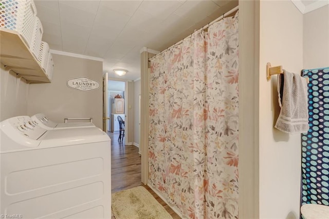 laundry room featuring laundry area, ornamental molding, wood finished floors, and washing machine and clothes dryer