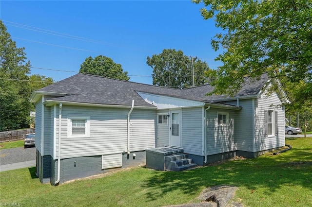 back of house featuring a lawn and a shingled roof