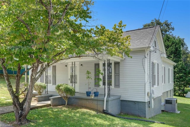 view of front of house featuring a porch, central AC unit, a front lawn, and roof with shingles