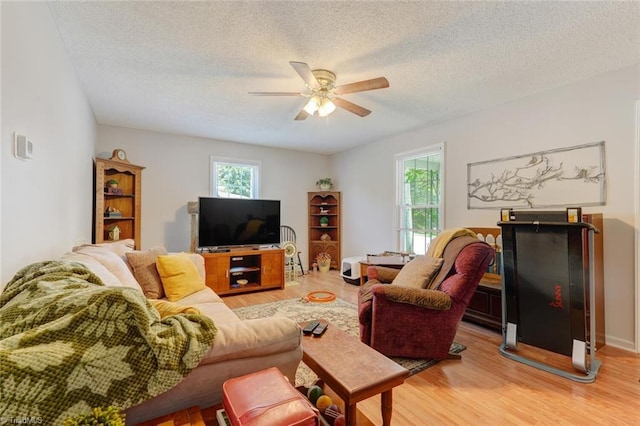 living room with light wood-style flooring, a textured ceiling, a healthy amount of sunlight, and ceiling fan