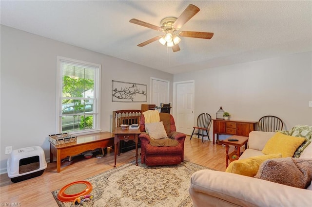 living room featuring a textured ceiling, a ceiling fan, and wood finished floors