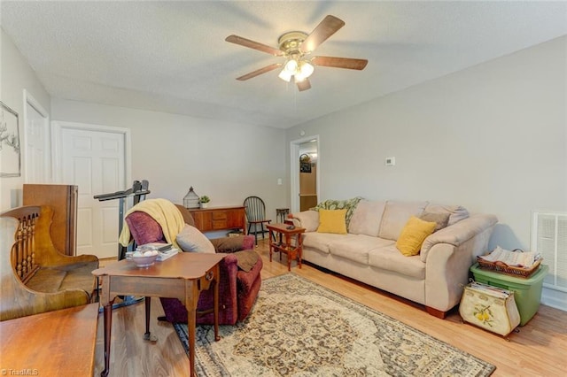 living room with visible vents, a textured ceiling, ceiling fan, and wood finished floors