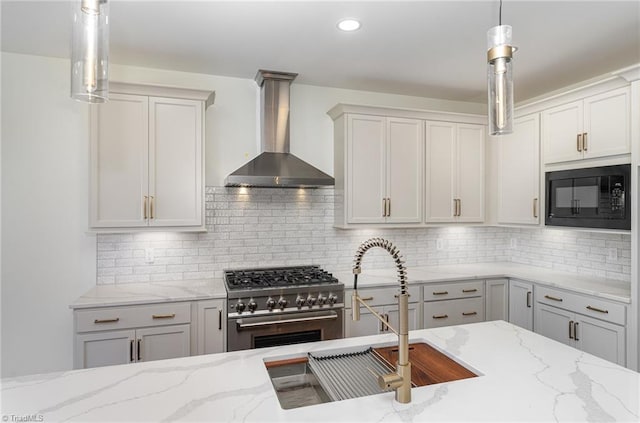 kitchen with high end stainless steel range oven, black microwave, decorative backsplash, wall chimney range hood, and pendant lighting