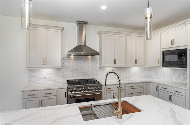 8812 Rudy Dr, Kernersville, NC 27284 - kitchen with wall chimney exhaust hood, stainless steel range, black microwave, light stone countertops, and recessed lighting