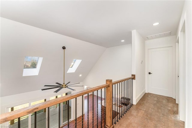 hallway with a wealth of natural light, light colored carpet, and vaulted ceiling