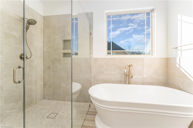 bathroom with tile walls and separate shower and tub