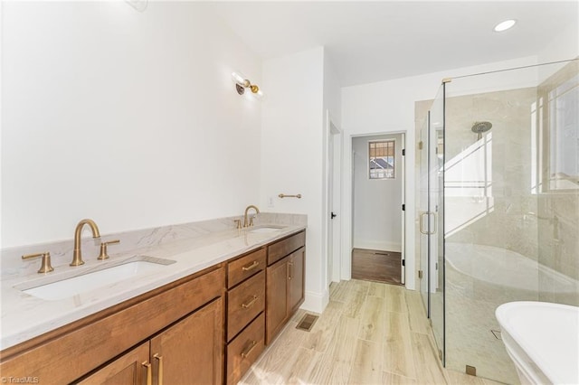 8812 Rudy Dr, Kernersville, NC 27284 - bathroom featuring a stall shower, a freestanding tub, wood finished floors, and double vanity
