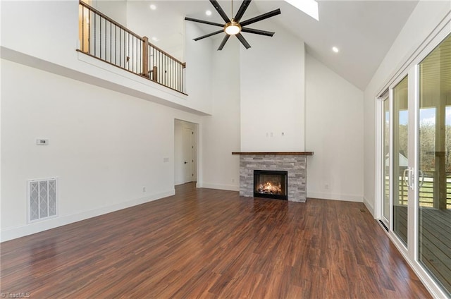 unfurnished living room with ceiling fan, dark hardwood / wood-style floors, a tile fireplace, and high vaulted ceiling