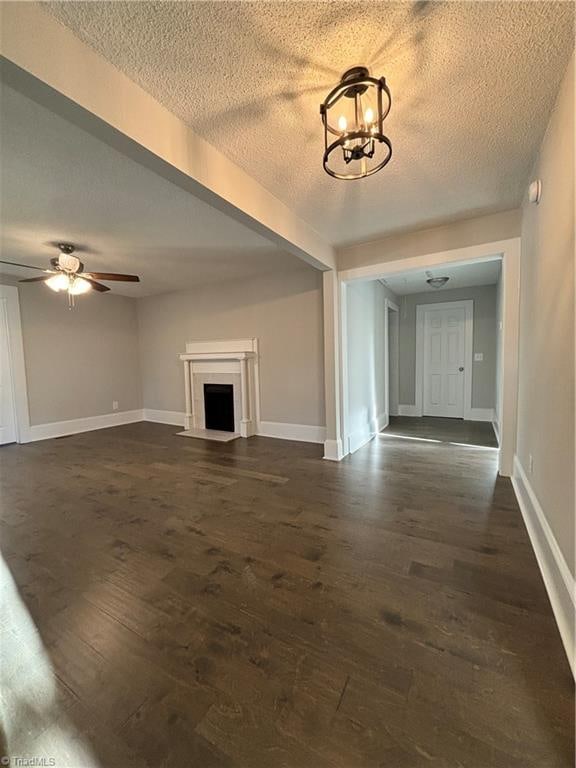 unfurnished living room with a textured ceiling, ceiling fan with notable chandelier, and dark hardwood / wood-style floors