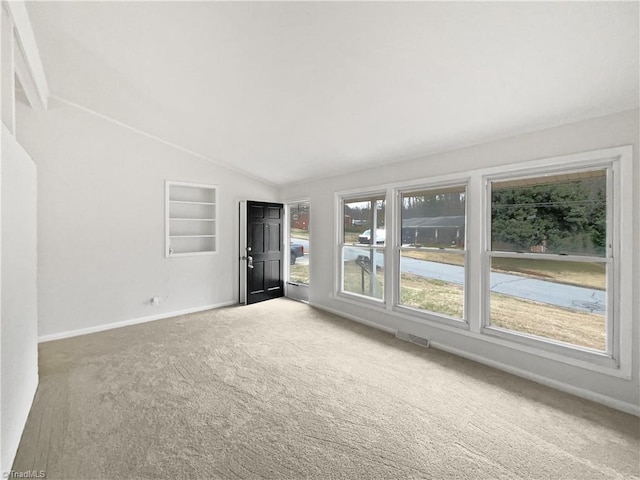 spare room featuring visible vents, carpet flooring, baseboards, and vaulted ceiling