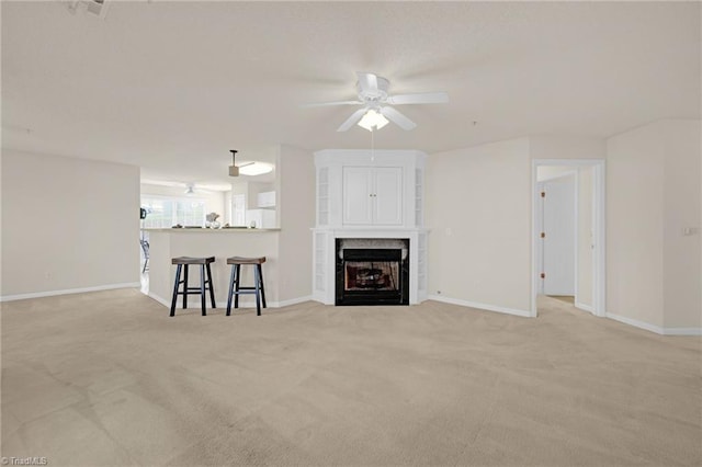 unfurnished living room with ceiling fan, light carpet, and a tile fireplace