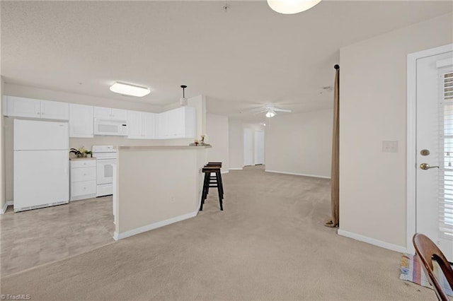 kitchen with light carpet, a breakfast bar, white cabinets, and white appliances