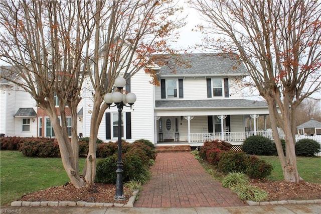 view of front of home with covered porch and a front lawn